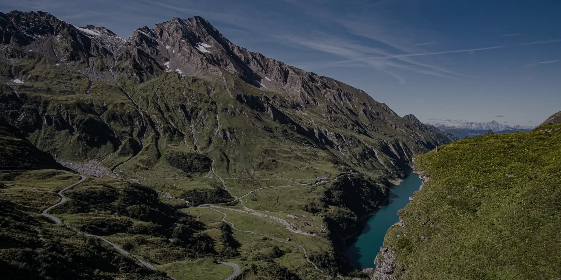 A road winding through an alpine valley above a lake