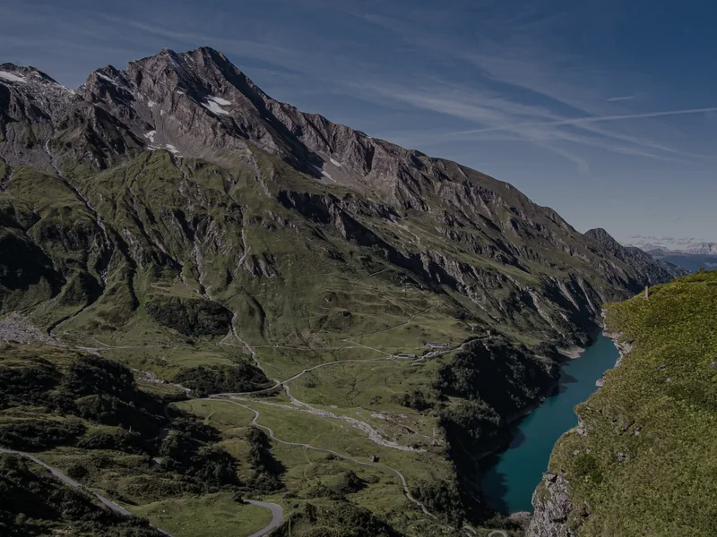 A road winding through an alpine valley above a lake